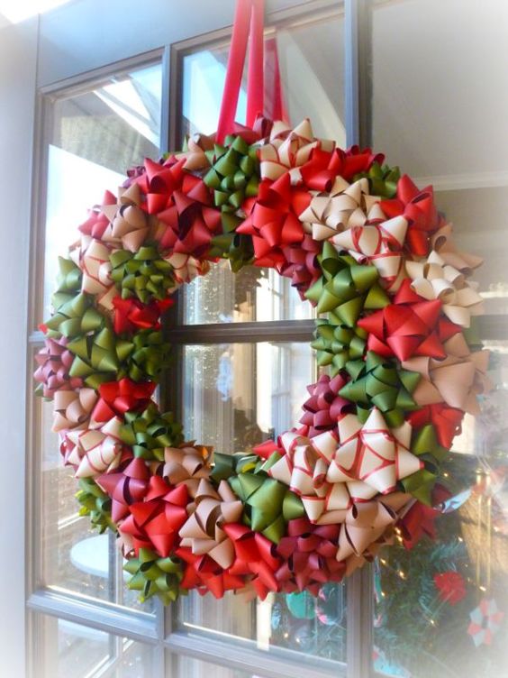 Christmas wreath made out of red, green and white bows hanging on windowed door. 