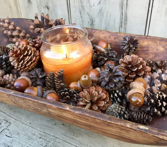 Candle in wood dish with pinecones and acorns. 