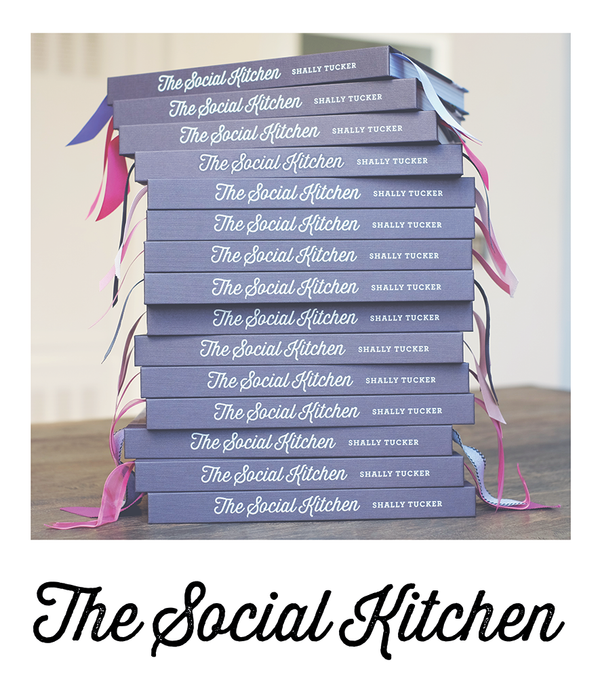 Side view stack of The Social Kitchen cookbooks.