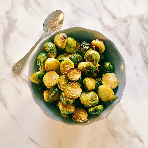 Top view of baked brussel sprouts in a green bowl. 
