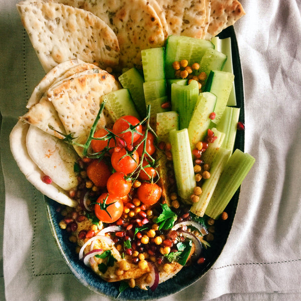 Plate of hummus with vegetables and pita. 