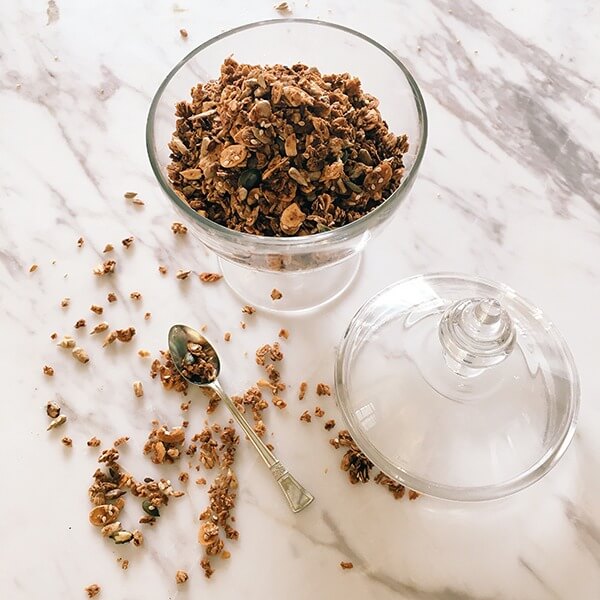 Top view of granola in glass jar on white marbled table.