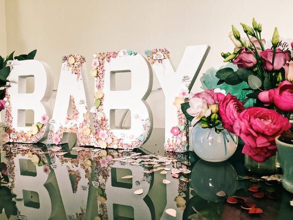 Block letters saying, "BABY" surrounded by flowers. 