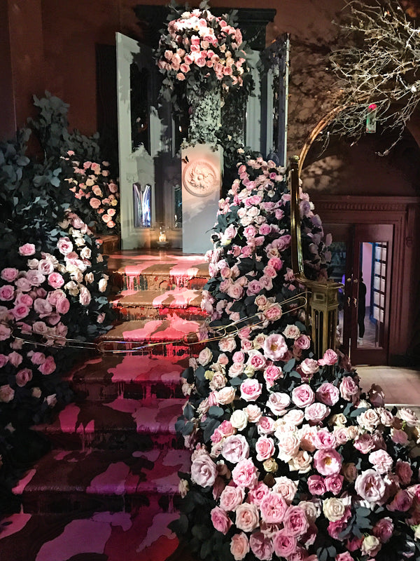 Staircase full of flowers leading up to a door.