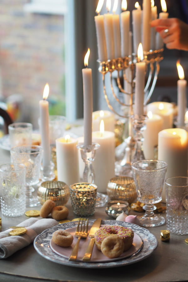 Table setting surrounded by candles and Chanukiah. 
