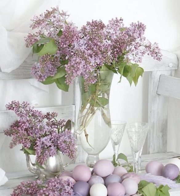 Flowers in a vase surrounded by purple dyed eggs. 