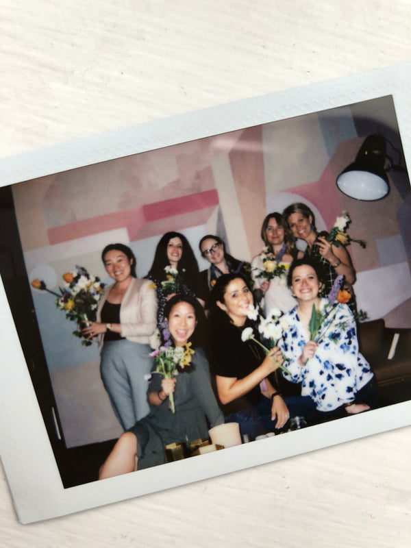 Polaroid of group of females smiling holding flowers. 