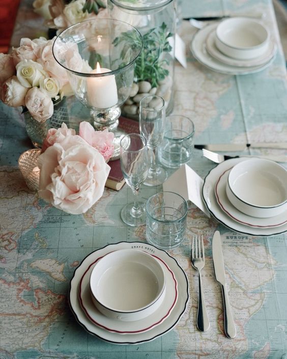 Top view of table setting with flower and candles on map tablecloth.