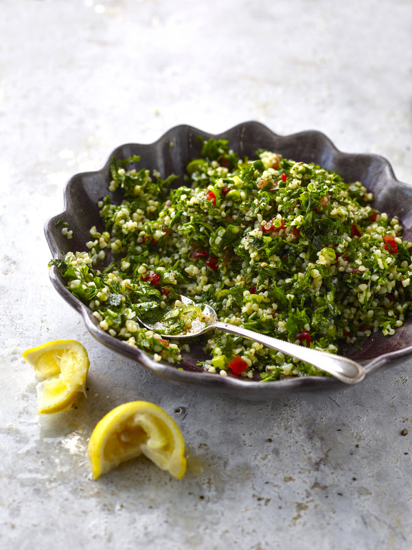 Tabbouleh Salad in a bowl with lemons on the side. 