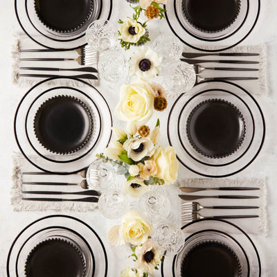 Top view of black and white table setting surrounded by flowers. 