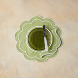 Top view of table setting with green napkin and placemat on beige background.