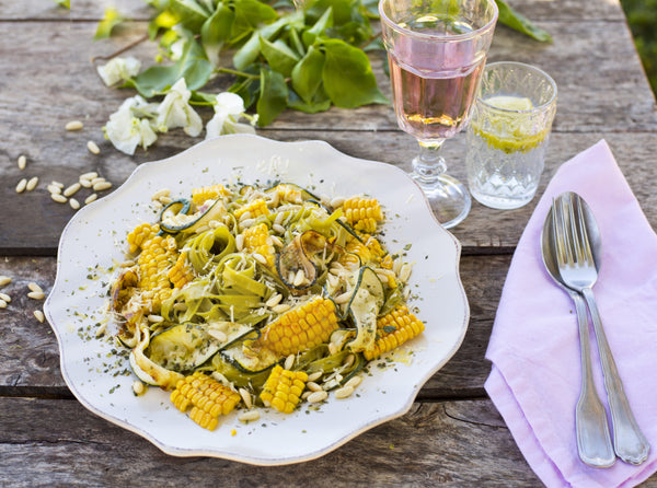 Spinach Tagliatelle With grilled courgette, Corn and Toasted Pine Nuts on a wooded table. 