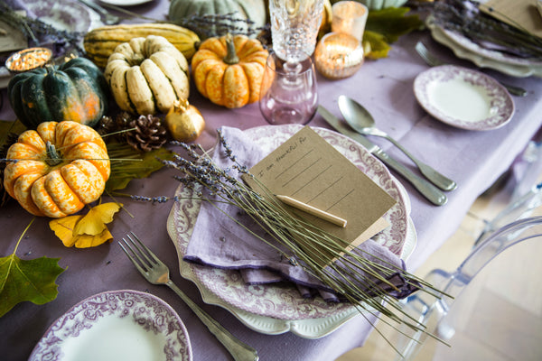 Top side view of table setting with pumpkins on purple tablecloth. 