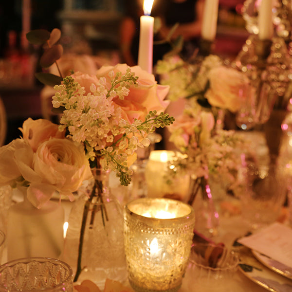 Flowers in a vase surrounded by candles on a table