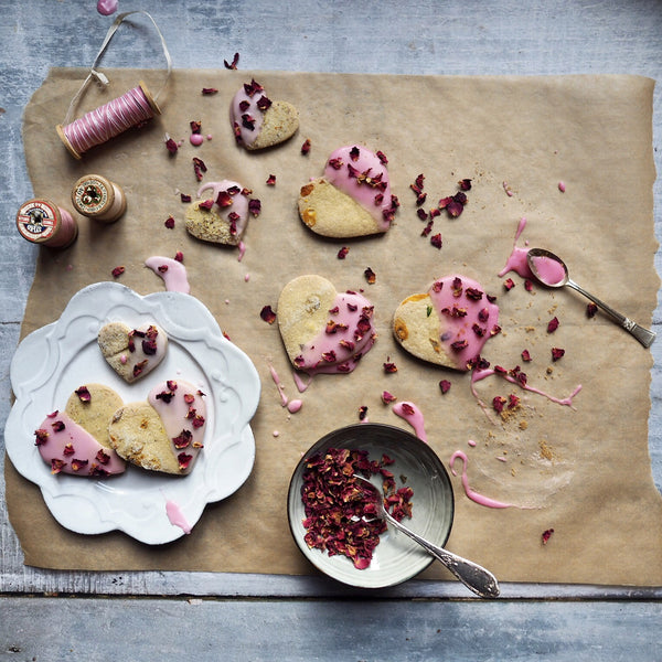 Top view of heart biscuits with pink and rose frosting on parchment paper. 