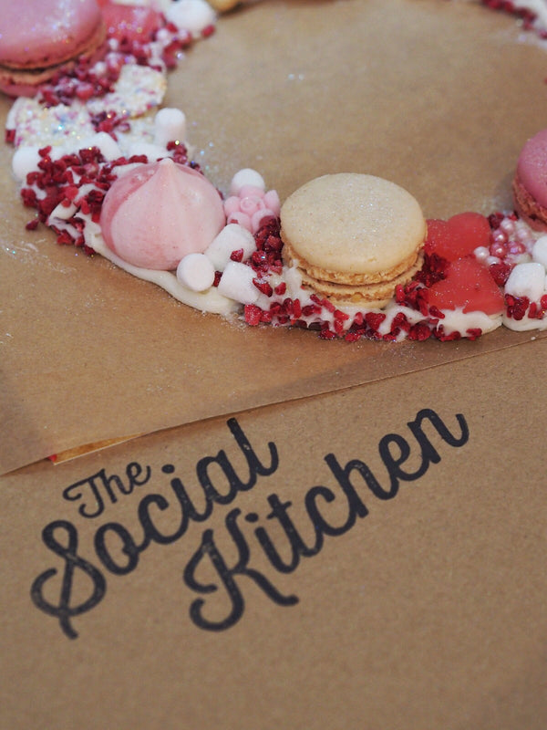 Text saying, "The Social Kitchen" with meringues and sprinkles on edible wreath.