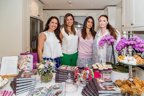 Dani Tucker and three females standing and smiling in front of table full of desserts and books. 