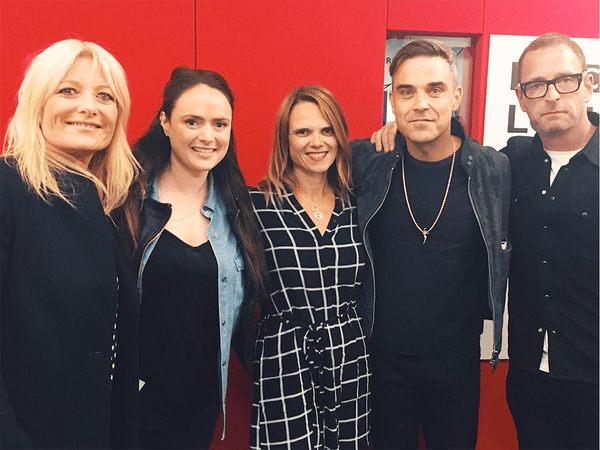 Dani Tucker standing next to BBC Radio London with Gaby Roslin & Robbie Williams. 