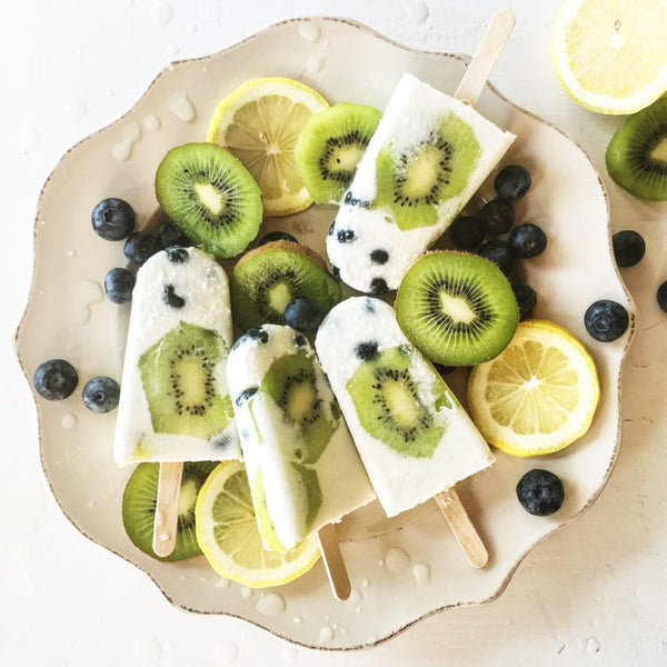 Top view of kiwi popsicles surrounded by fruits. 