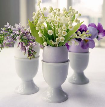 Three flower settings with purple dyed eggs in egg holders. 