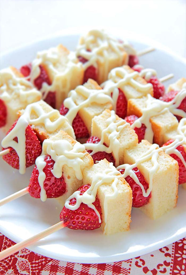 Plate full of strawberry and cake kebobs.
