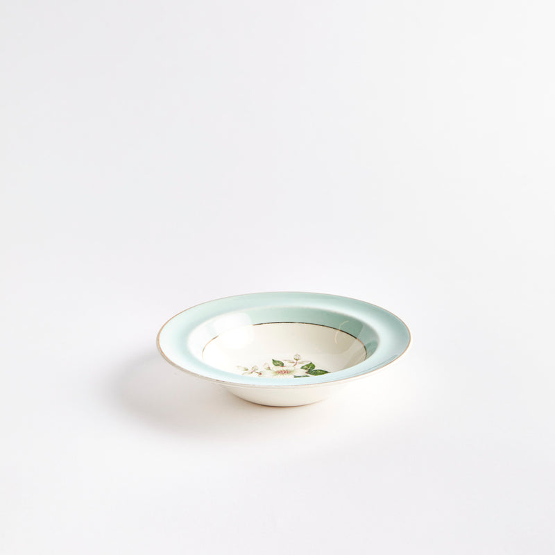 White bowl with flower in the center, light blue edge and gold rim.