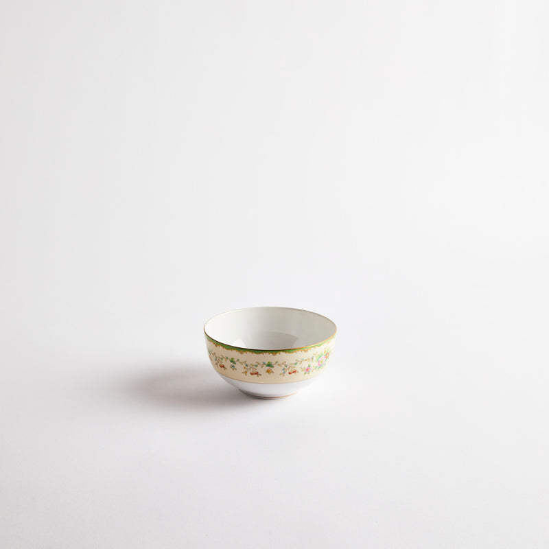 White and cream bowl with green floral pattern rim. 