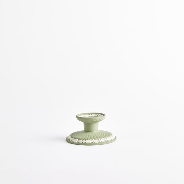 Green candle holder with white floral detail.