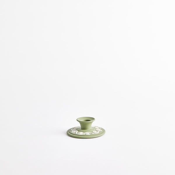 Green candle holder with white design.