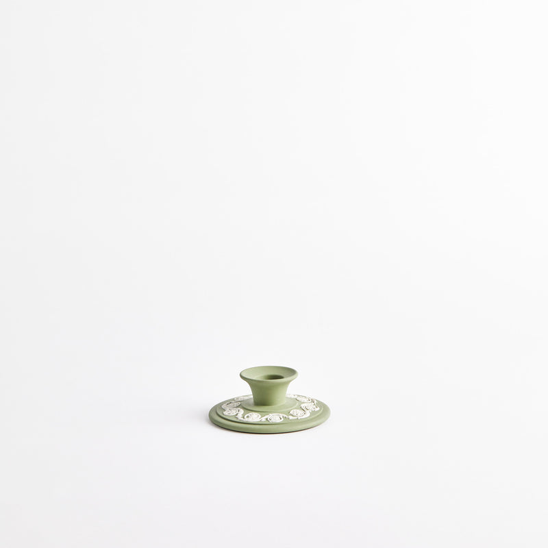 Green candle holder with white design.