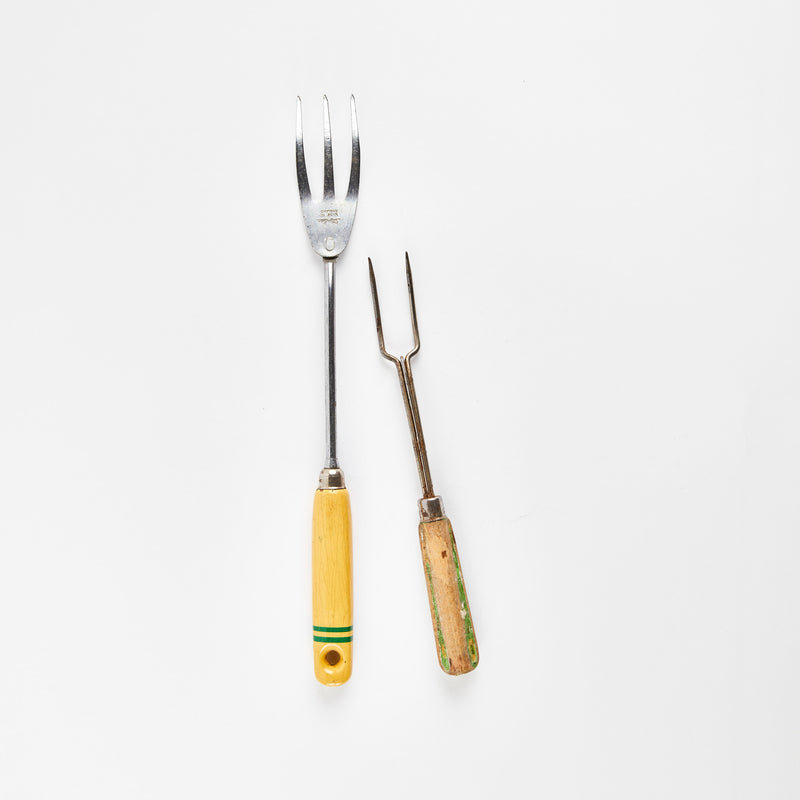 Two silver carving forks with a yellow and wooden handle.