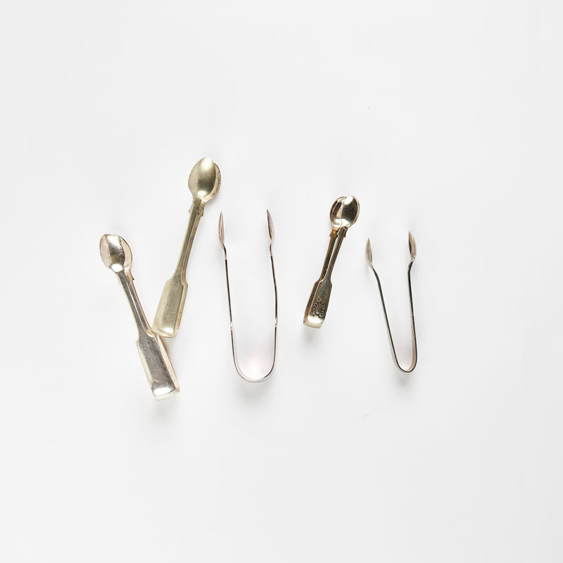 Four silver ice tongs.