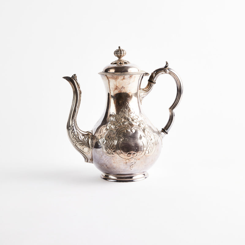Silver with intricate design coffee pot.