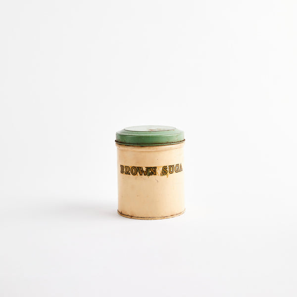 Silver metal container with green lid and text.