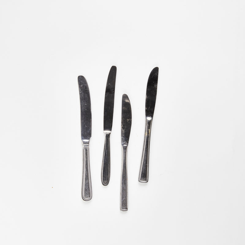 Four silver butter knives.