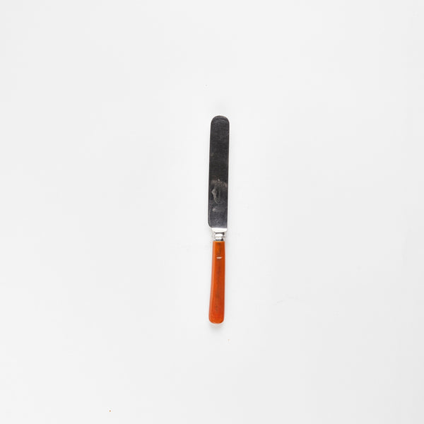 Silver butter knife with orange handle.