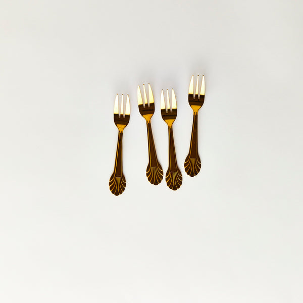 Four gold cake forks with scalloped edge handle.
