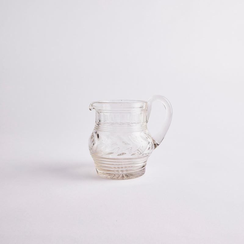 Clear glass jug with embossed design.
