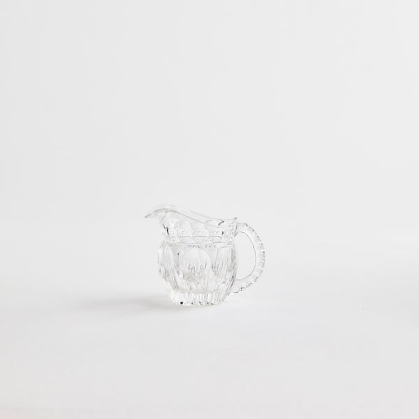 Clear glass jug with embossed design.