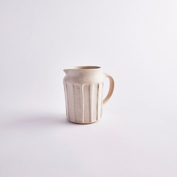 Cream ceramic jug with ripple detailing.