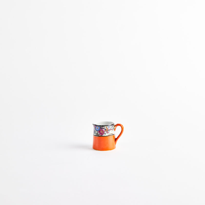 Orange ceramic jug with multicolour floral design.