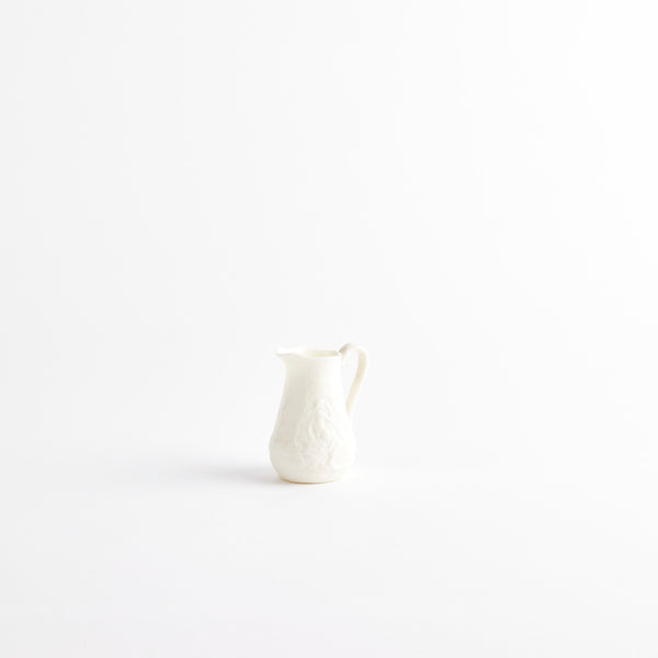 White ceramic jug with embossed design.