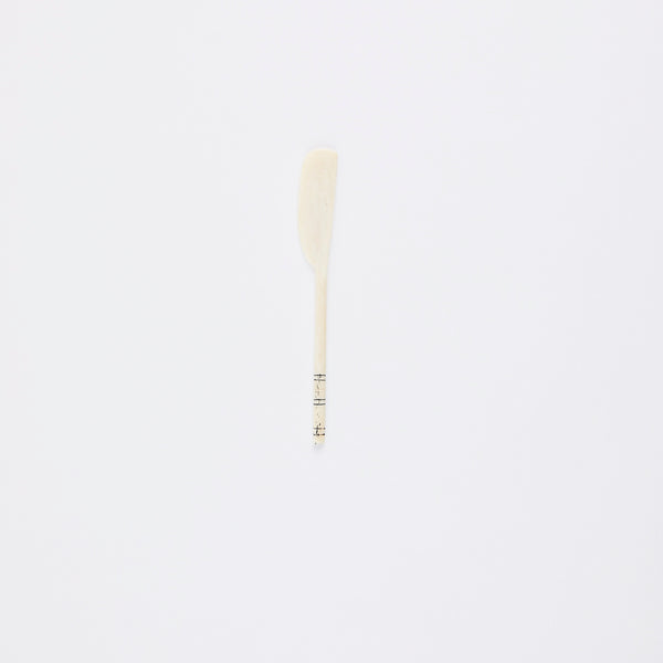 Cream bone spoon with black lines on handle.