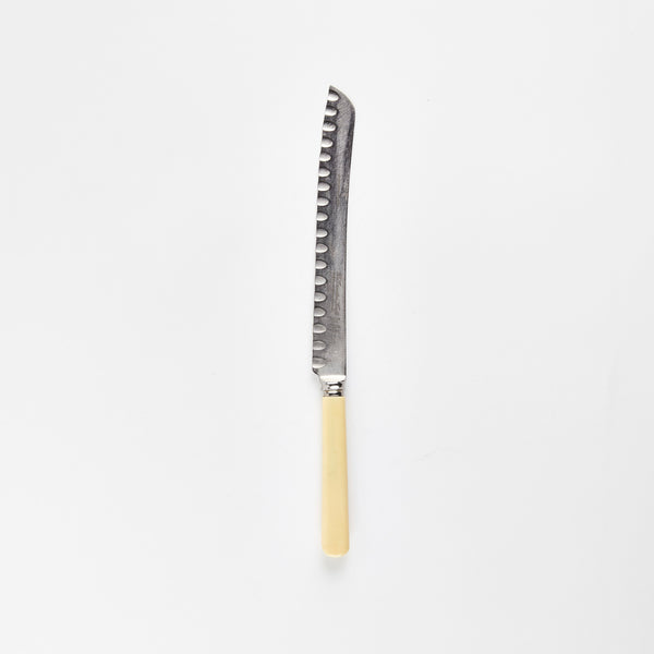 Silver bread knife with cream handle.
