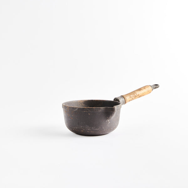 Cast iron pot with wooden handle.