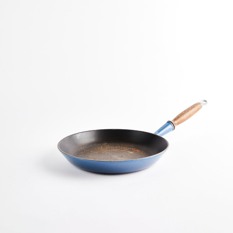 Blue cast iron pan with wooden handle.