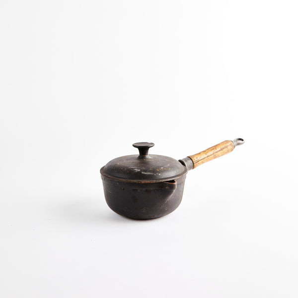 Cast iron pot with wooden handle and lid.