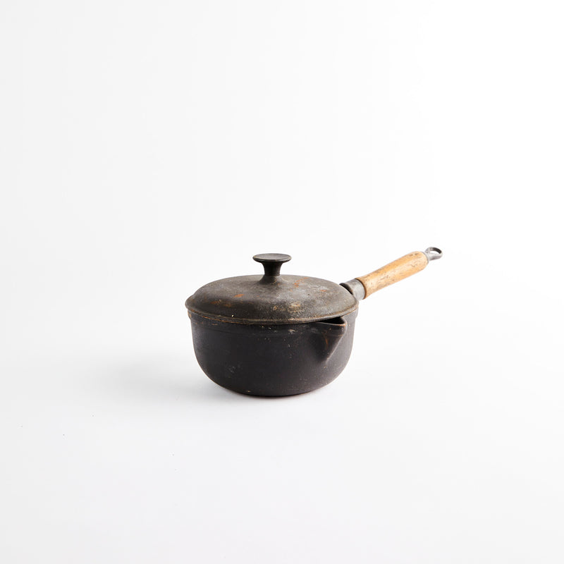Cast iron pot with wooden handle and lid.