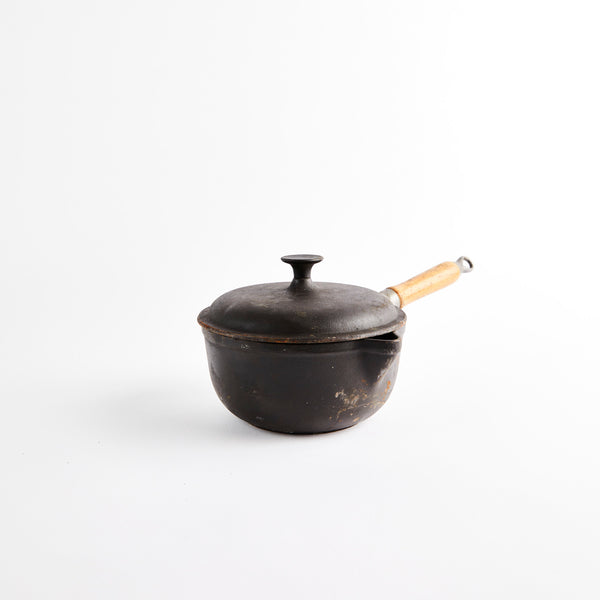 Cast iron pot with wooden handle and lid.