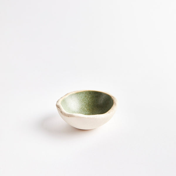 Cream ceramic pinch pot with green interior.